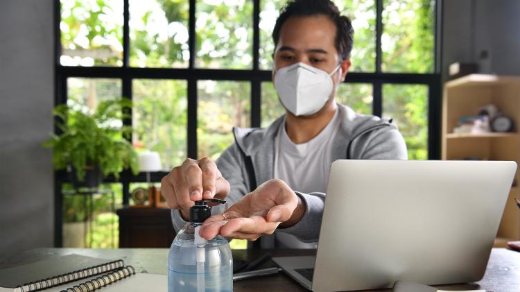 A man wearing a mask uses alcohol in his hands and isolates social isolation due to the Corona virus - Getty Images - Getty Images